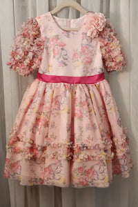 Floral dress with pink flowers on a hanger against a neutral background